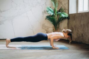 reine em casa com pouco equipamento: pessoa fazendo exercícios funcionais usando halteres leves e um colchonete, em um ambiente doméstico organizado.
